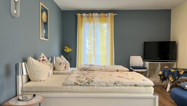 Zwei-Bett-Zimmer mit Fernseher und Sitzecke